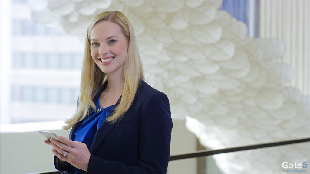 woman working in office smiling at camera with an ipad for promotional video