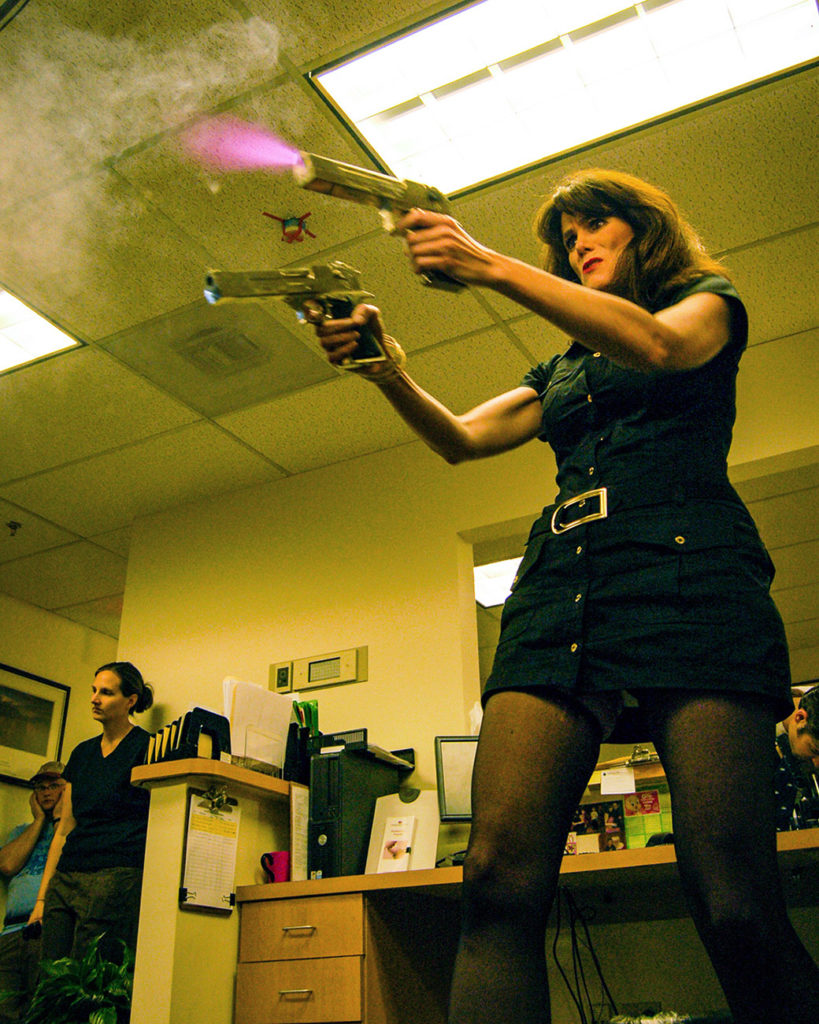 woman firing guns in office in behind the scenes film set photo