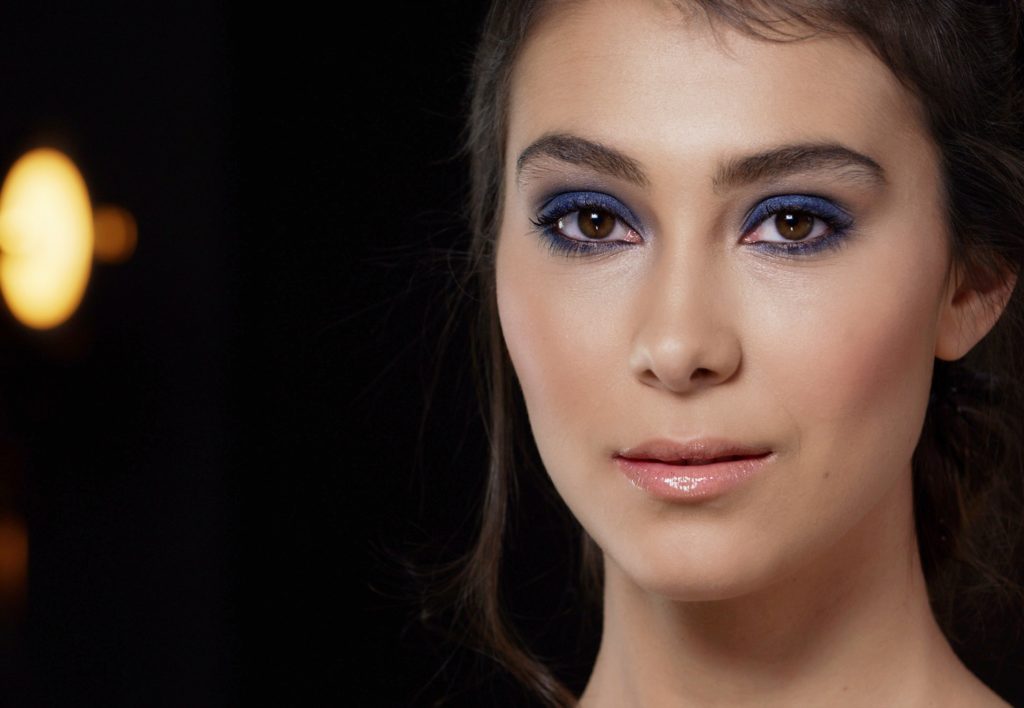 female makeup model for beauty tutorial training video against dark background