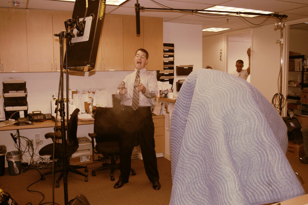 a man fires guns at his coworkers in behind the scenes film set photo