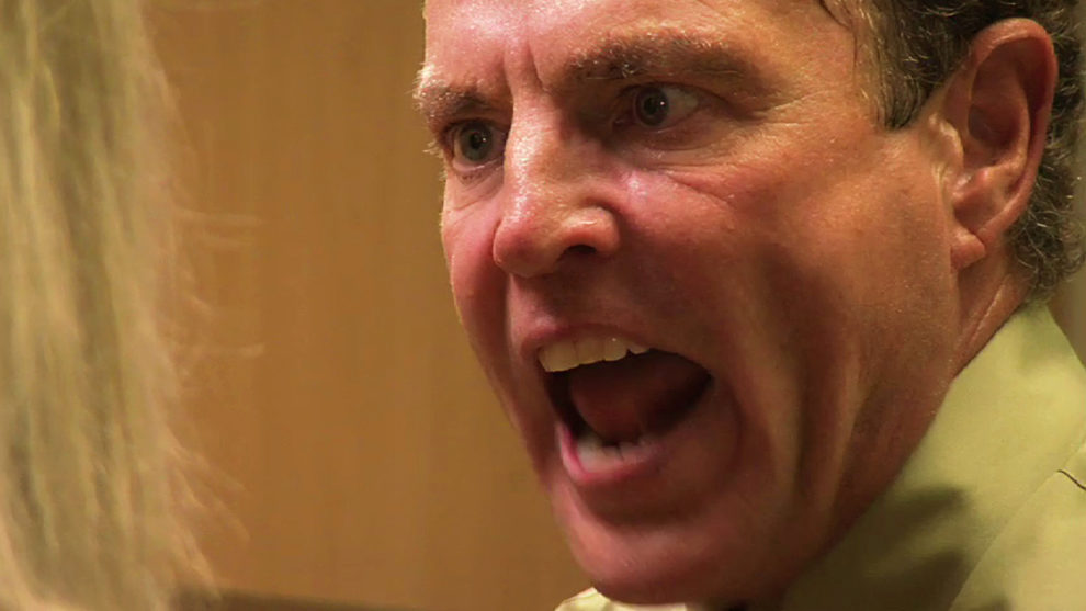 the angry face of a boss after an employee throws hot coffee in his face