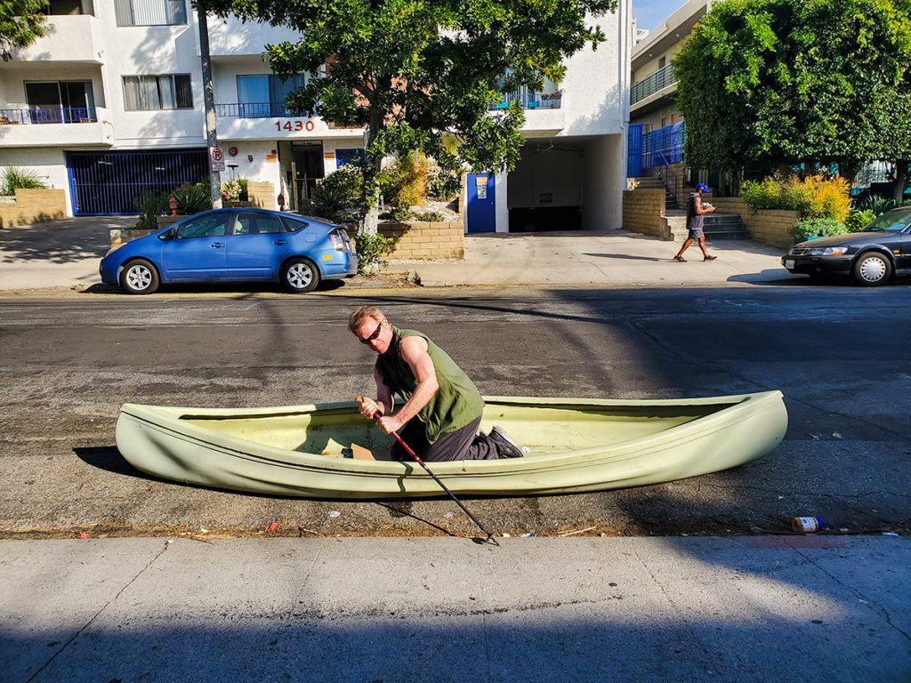 a man rows a canoe in a city street