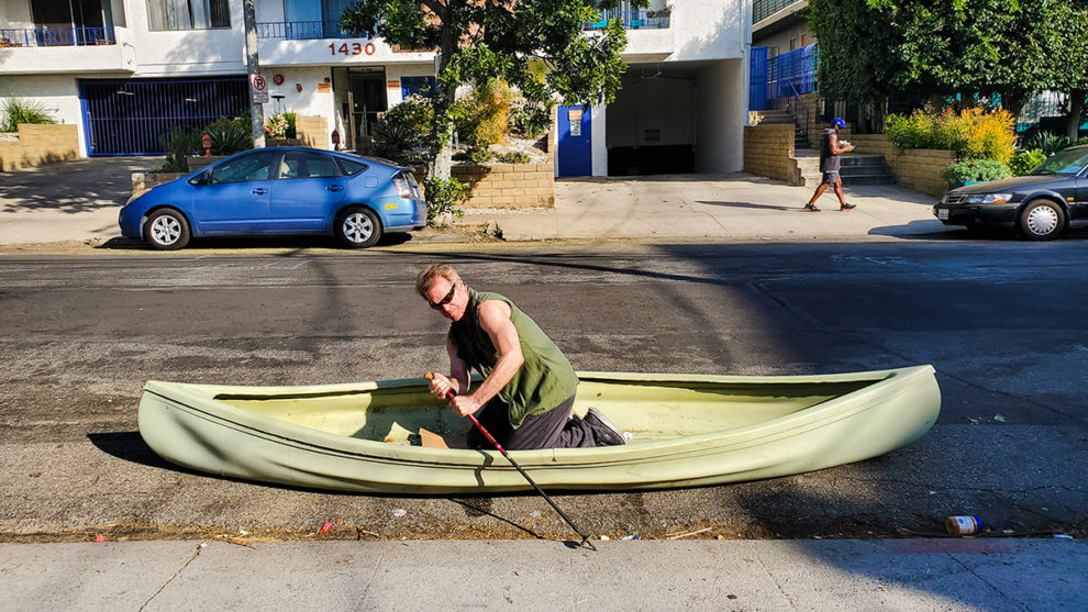 a man rows a canoe in a city street