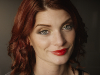 portrait of model with red hair and lips and green eyes for a fashion film