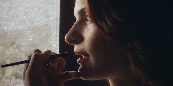 a female readhead actor gets her makeup done by window light